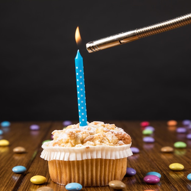 Foto primer plano de pastel con vela encendida en la mesa contra un fondo negro