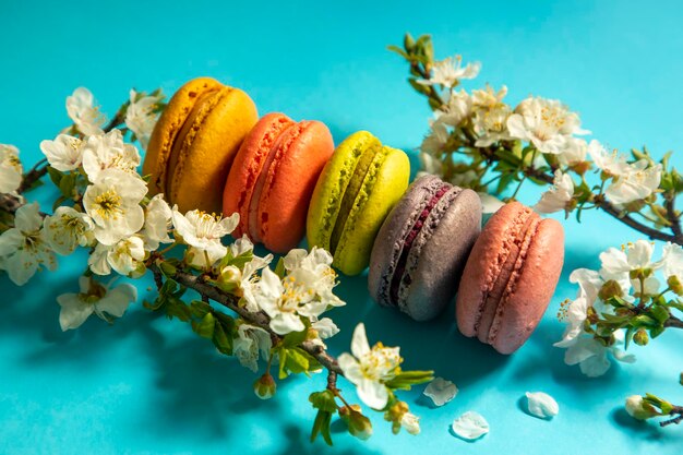 Primer plano de pasteles macarons de diferentes colores en fondo azul Concepto culinario y de cocina Sabrosos macarrones coloridos