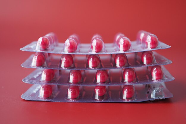 Primer plano de las pastillas del paquete de ampollas de fondo rojo