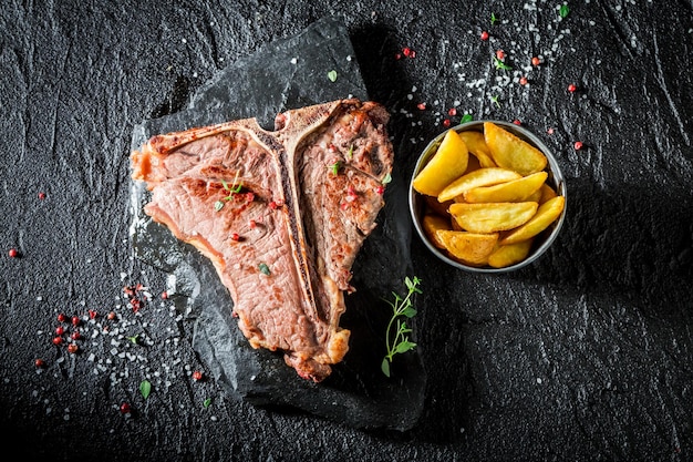 Primer plano de patatas fritas y bistec tbone en la roca negra