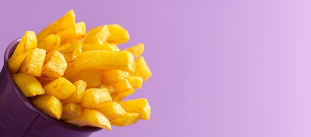 Primer plano de patatas fritas en un cubo aislado en un estandarte de fondo sin costuras púrpura añadir