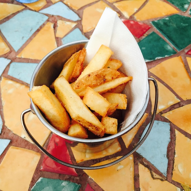 Foto primer plano de patatas fritas en un recipiente servidas en la mesa