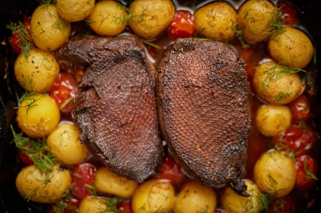 Primer plano de pecho de pato o ganso asado Servido con patatas al horno y tomates cereza Vista superior plana