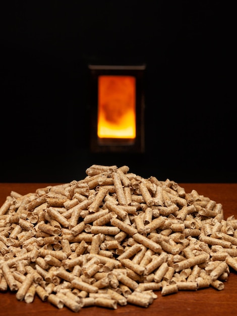 Foto primer plano de pellets de madera en la mesa contra el fuego y el fondo negro