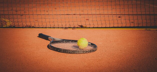 Primer plano de la pelota de tenis y la raqueta en la cancha