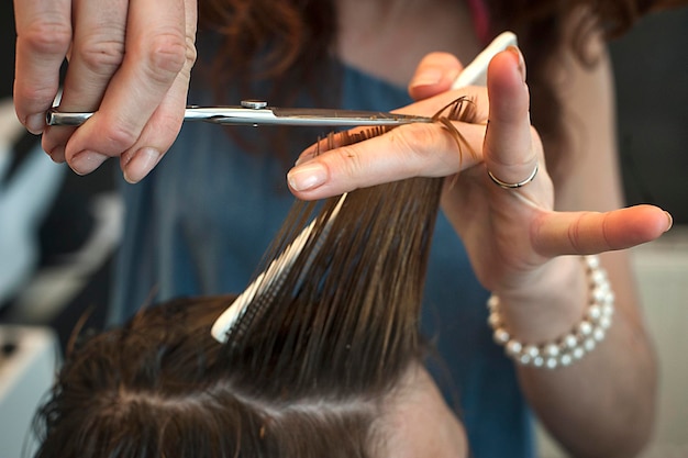 Primer plano de una peluquera cortando el cabello de un hombre