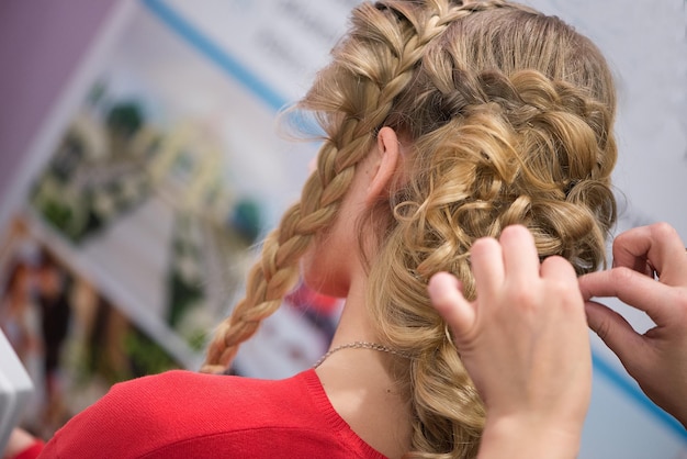 Foto primer plano de una peluquera sosteniendo el cabello rubio de los clientes en el salón.