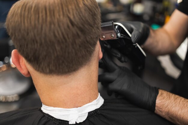 Primer plano de un peluquero cortando el cabello de un cliente con una maquinilla eléctrica