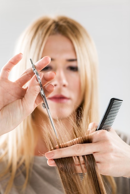 Primer plano de un peluquero cortando el cabello de una mujer. Enfoque selectivo.