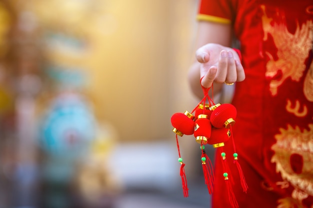 Foto primer plano de la pequeña mujer asiática vistiendo rojo cheongsam chino tradicional, mantenga pequeñas decoraciones de linterna para el año nuevo chino
