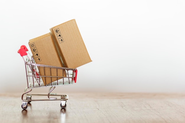 Primer plano de un pequeño carrito de compras con cajas de cartón en la mesa