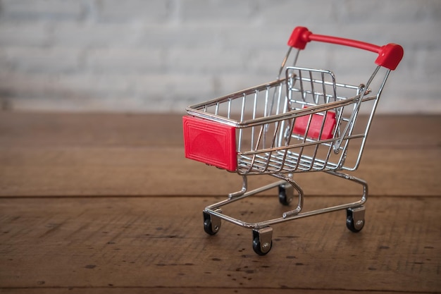 Primer plano de un pequeño carrito de compras en una mesa de madera contra la pared