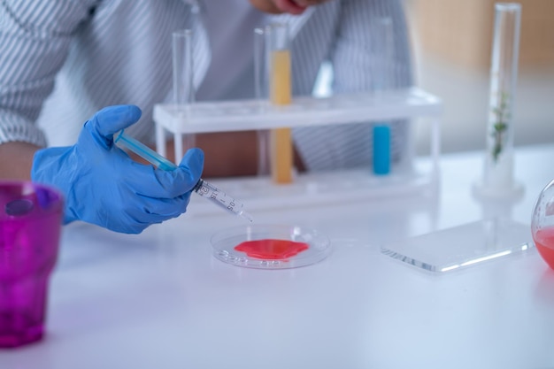 Primer plano de una persona en una bata de laboratorio que trabaja con reactivos