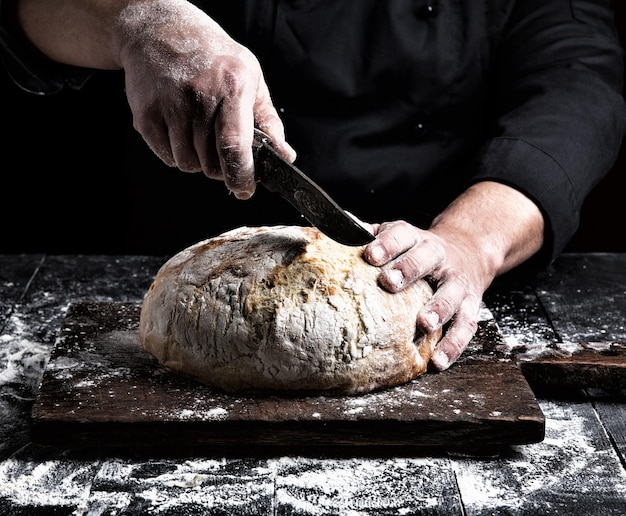 Primer plano de una persona cortando pan con un cuchillo en el mostrador