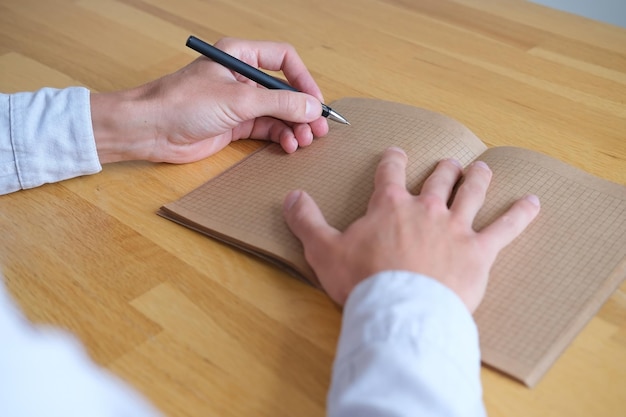 Primer plano de una persona escribiendo en papel vintage de cuaderno kraft