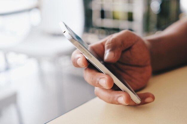 Primer plano de una persona con un teléfono móvil en la mesa