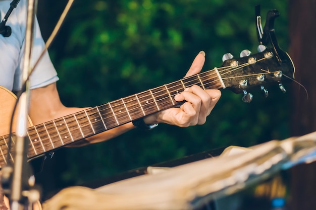 Primer plano de persona tocando la guitarra con fondo borroso