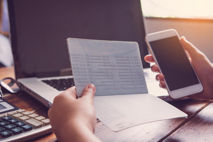Foto primer plano de una persona usando el teléfono mientras sostiene la libreta de pases
