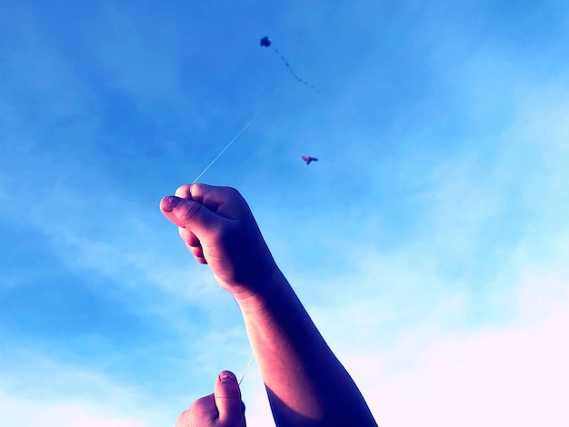 Primer plano de una persona volando cometa contra el cielo