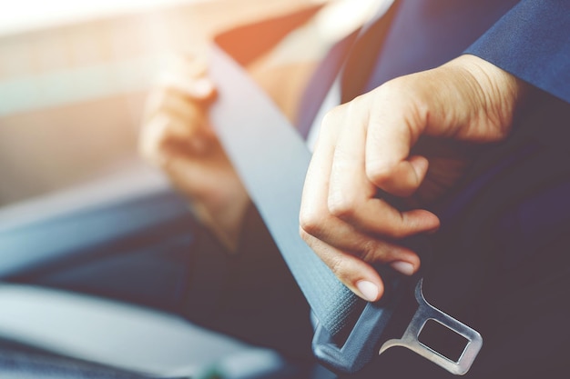 Primer plano de personas mujer mano sujetando el cinturón de seguridad del asiento en el automóvil por seguridad antes de conducir en la carretera concepto transporte viaje enfoque suave