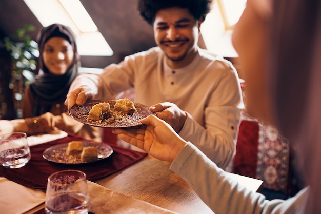 Primer plano de personas musulmanas comiendo baklava como postre en casa