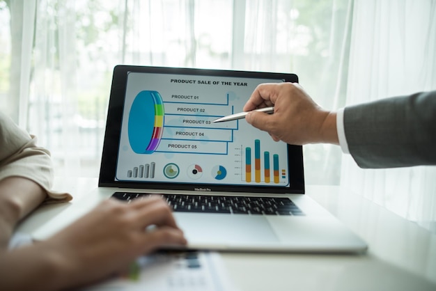 Primer plano de personas de negocios trabajando en un gráfico mientras usan una computadora portátil en la oficina