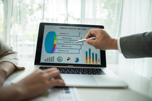 Foto primer plano de personas de negocios trabajando en un gráfico mientras usan una computadora portátil en la oficina