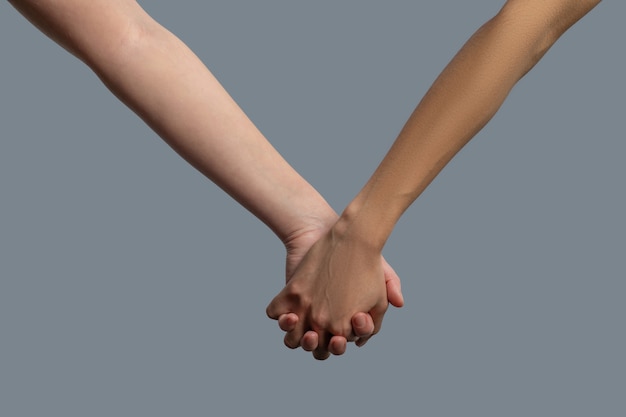 Foto primer plano de personas de piel clara y de piel oscura tomados de la mano