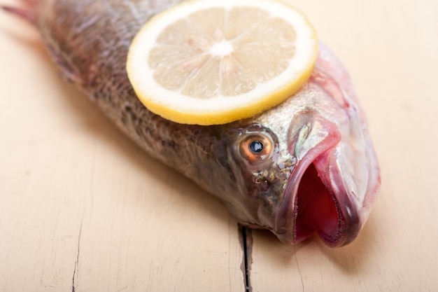 Foto primer plano de pescado fresco con rebanada de limón en la mesa