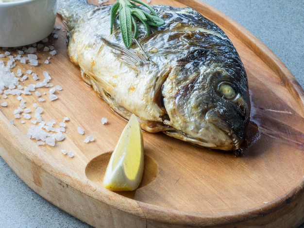 Foto primer plano de pescado fresco con rebanada de limón y sal en la tabla de cortar