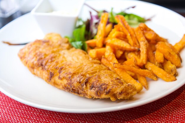 Foto primer plano de pescado y papas fritas en un plato sobre la mesa