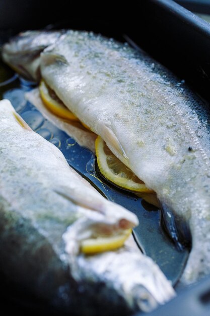 Primer plano de pescado relleno de limones fritos en una sartén con aceite