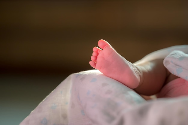 Primer plano de un pie de bebé en la cama a la luz del sol de la mañana