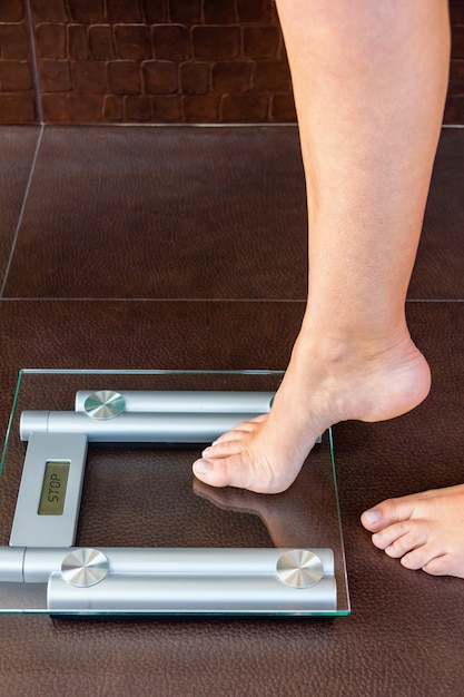 Foto primer plano de un pie de mujer subiendo a la báscula de baño. concepto de salud y peso