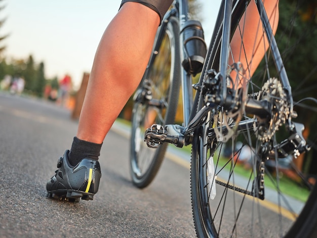 Primer plano de las piernas del ciclista masculino con zapatos de ciclismo de pie con una bicicleta