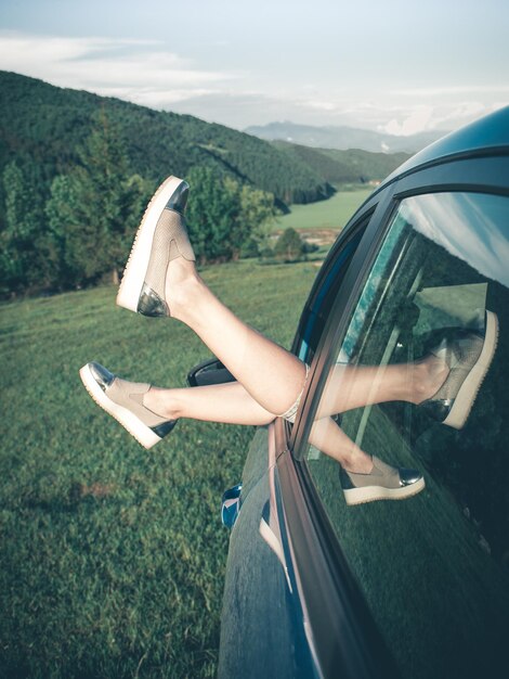 Primer plano de las piernas en coche en la carretera contra el cielo