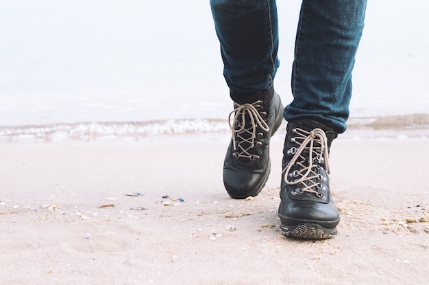 Primer plano de piernas femeninas en las botas de invierno están en la playa