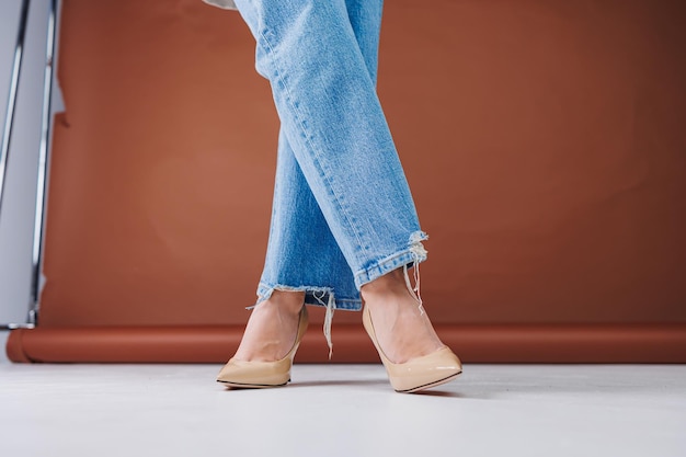 Primer plano de piernas femeninas en jeans azules y elegantes tacones beige