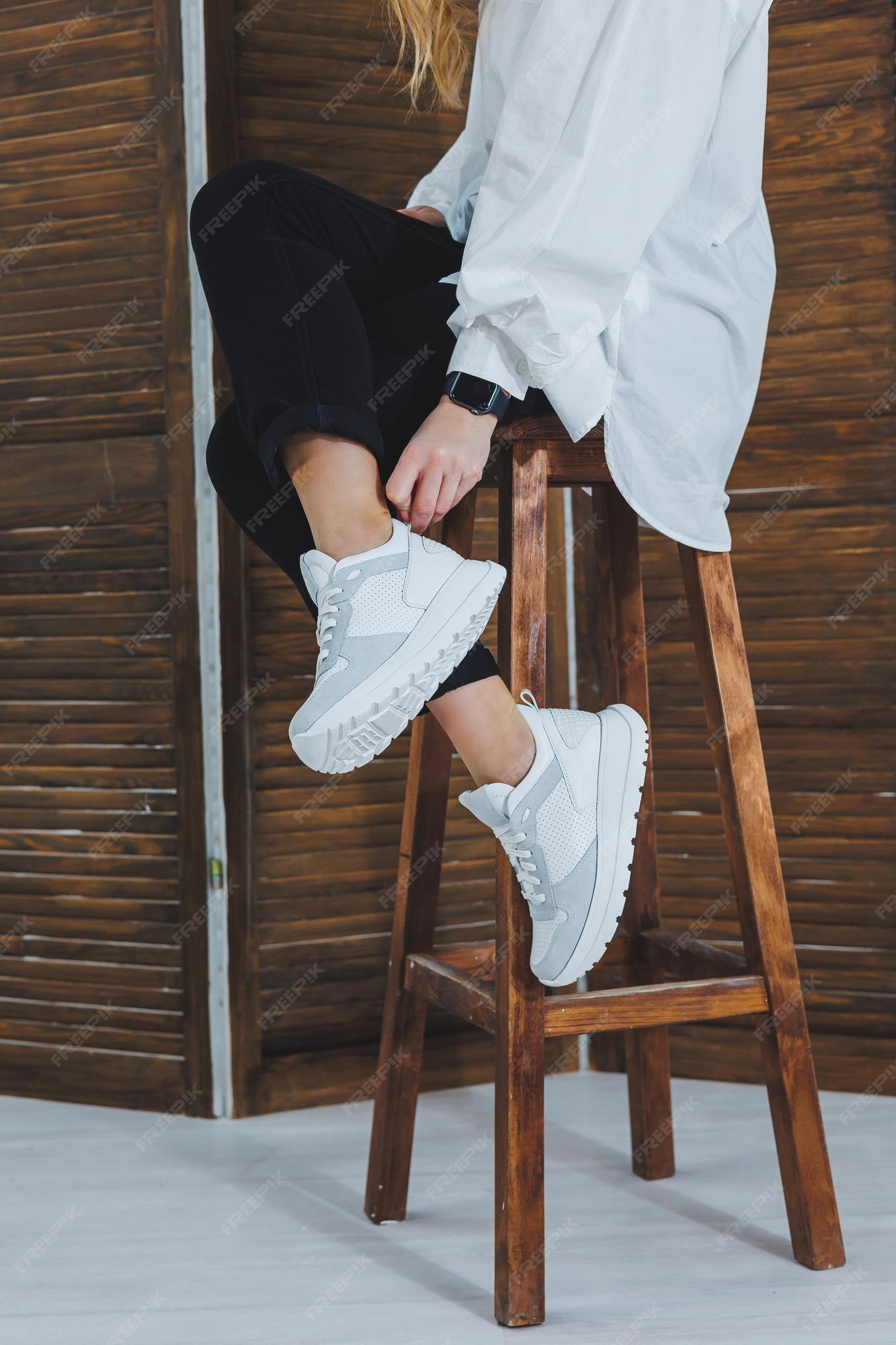 Primer plano de piernas femeninas en jeans negros en elegantes zapatillas blancas de cuero mujer de zapatillas nuevas colección moderna de temporada de zapatillas con estilo moda femenina | Foto