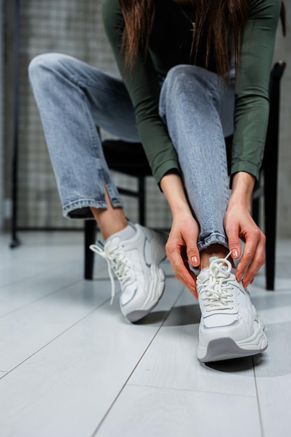 Primer plano de piernas femeninas en jeans y zapatos en zapatillas de deporte de moda primer plano Zapatos de moda para mujeres todos los días