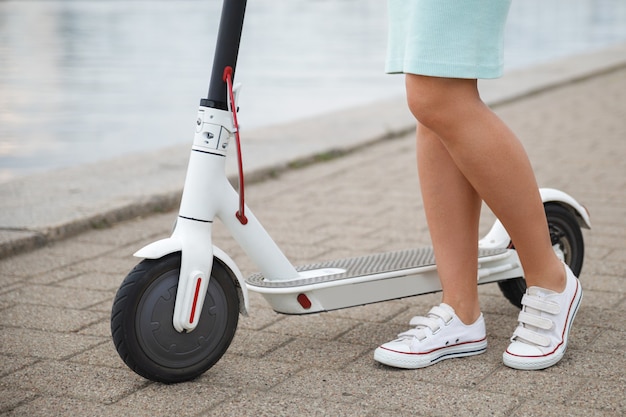 Primer plano de las piernas femeninas en el scooter eléctrico