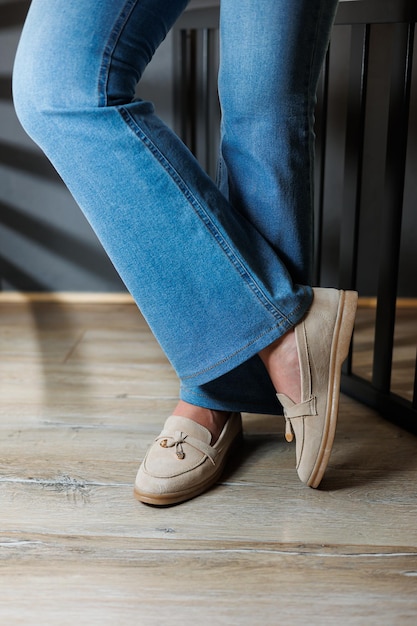 Primer plano de piernas femeninas en vaqueros y mocassines beige hechos de cuero genuino