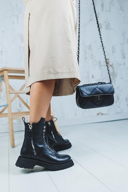 Primer plano de piernas femeninas en zapatos con cordones de cuero negro Bolso de cuero negro en manos femeninas Nueva colección de otoño de zapatos de cuero para mujer 2022