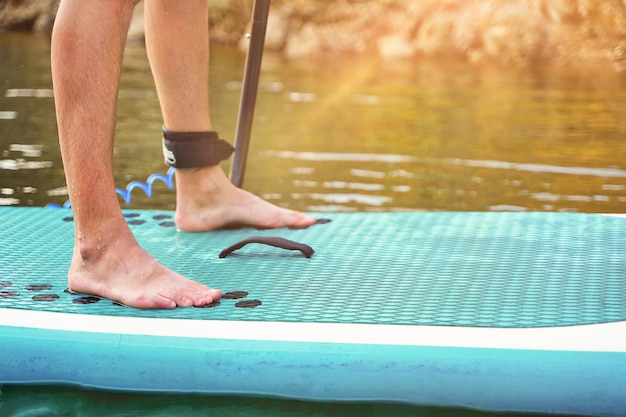 Primer plano de las piernas de un hombre en paddle board en agua