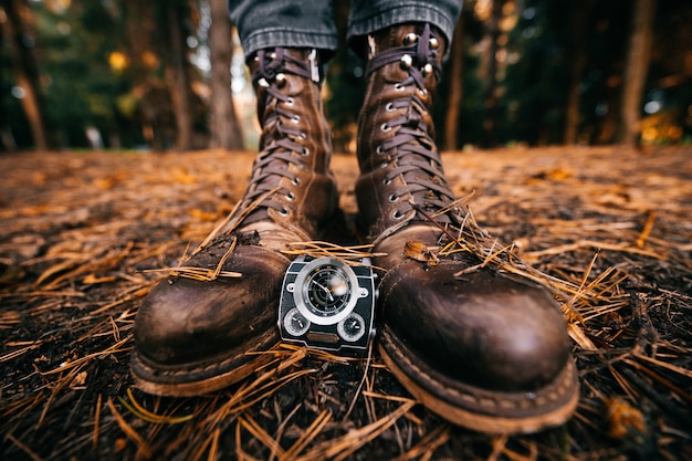 Primer plano de las piernas masculinas en hipster vintage botas de pie en otoño molido con agujas de pino.