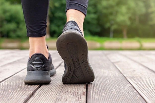 Primer plano de las piernas de las mujeres en zapatillas negras caminando sobre una plataforma de madera