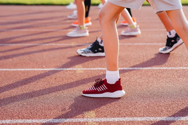 Primer plano de las piernas de niños y niñas al comienzo antes de correr y practicar deportes en el estadio durante la puesta de sol Estilo de vida saludable