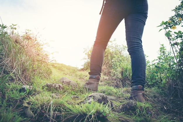 Primer plano de los pies de caminante femenino caminando en la pista forestal. Mochilero mujer activa viajando en la naturaleza.