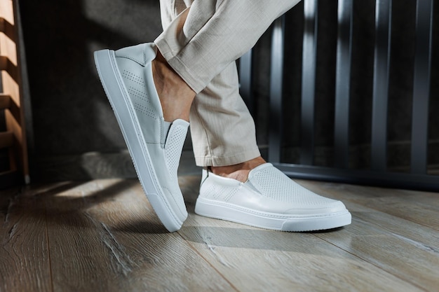 Primer plano de pies masculinos en zapatos casuales blancos joven de moda de pie en cuero mocasín blanco elegante en pantalones de moda zapatos de verano de temporada para hombres estilo calle casual