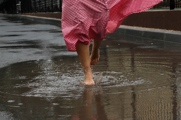 Primer plano de los pies de una niña bailando en un charco después de una lluvia de verano.